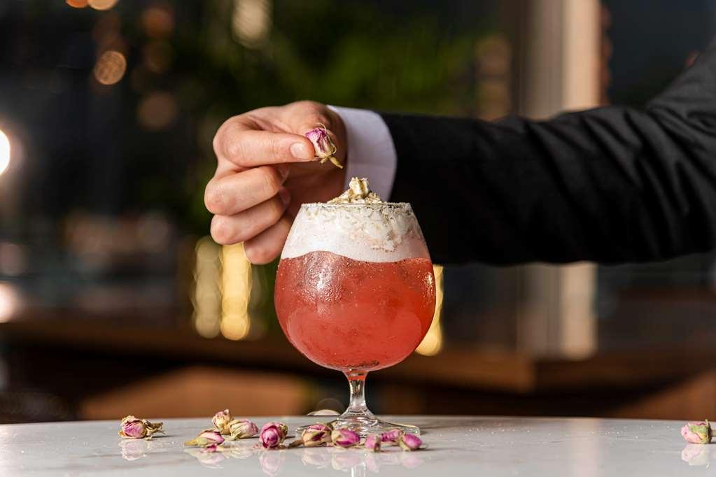 Aleph Doha Residences, Curio Collection By Hilton Restoran fotoğraf A bartender adding a rose petal to a cocktail